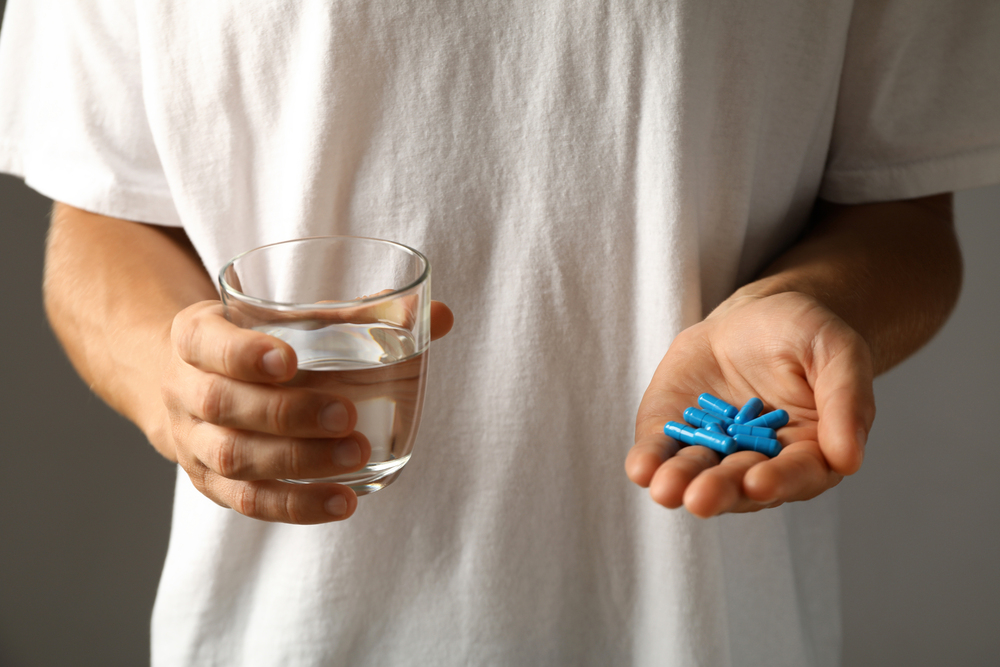 Male holding blue pills