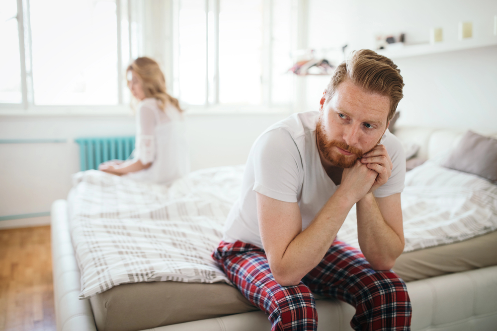 Unhappy young couple sitting on a bed