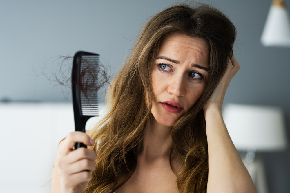 Woman suffering from hair loss holding a hairbrush