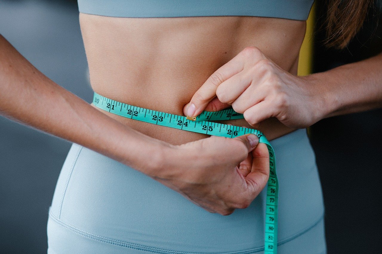 Woman measuring waist with tape measure