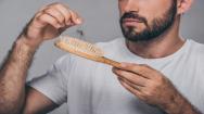 Male with Hair Loss Looking at A Hairbrush