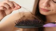 Woman untangling hair from a hairbrush