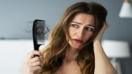 Woman suffering from hair loss holding a hairbrush